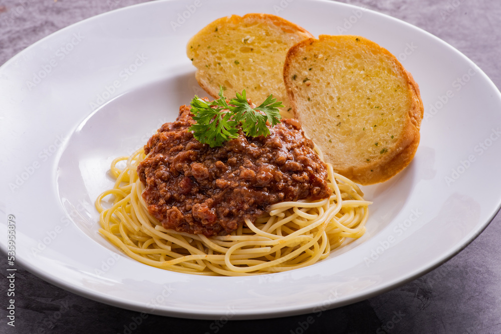 Healthy plate of Italian spaghetti topped with a tasty tomato and ground beef Bolognese sauce with garlic bread Healthy plate of Italian spaghetti topped with a tasty tomato and ground beef Bolognese sauce with garlic bread