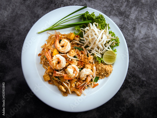Pad Thai with shrimp and vegetables on a dark background, view from above