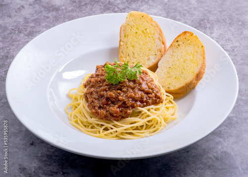 Healthy plate of Italian spaghetti topped with a tasty tomato and ground beef Bolognese sauce with garlic bread