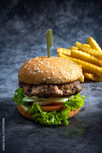 Craft beef burger and french fries on black background.