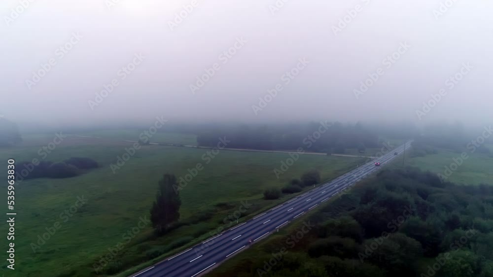 Cars driving along countryside road on foggy day. Aerial sideways Cars driving along countryside road on foggy day. Aerial sideways