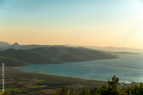 Beautiful morning landscape with sea mountains and rural fields.