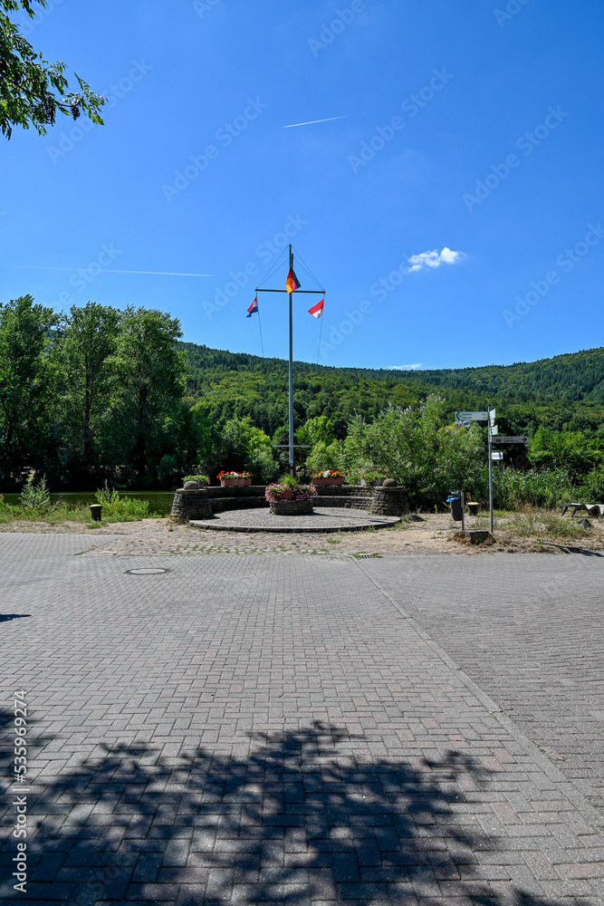 Fototapeta premium Fahnenmast am Mainländle in Gemünden am Main, Main-Spessart in Unterfranken, Franken, Bayern Deutschland bei blauem Himmel
