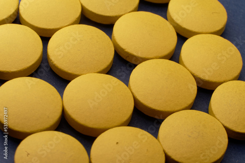 Yellow pills on a blue background. The pills are in the foreground, background is blurred out to give some depth. It's a macro image with a healthcare feel, so it fit well in ad for pharmaceuticals
