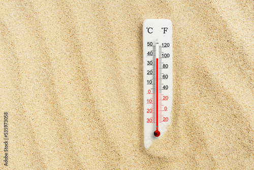 Hot summer day. Celsius and fahrenheit scale thermometer in the sand. Ambient temperature plus 37 degrees