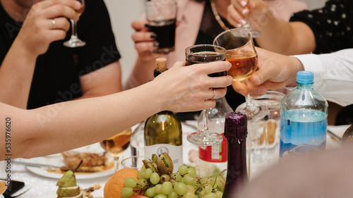 group of friends clink glasses with wine and celebrate the holiday at a festive table