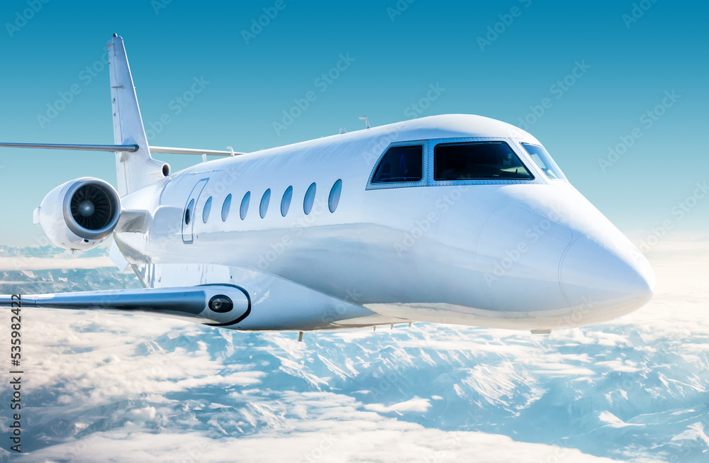 Close-up white modern luxury executive airplane fly over snow covered mountains