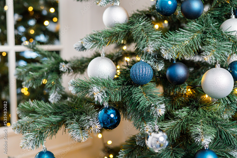 Christmas tree with blue and silver toys. Festively decorated Christmas tree with garlands. Symbol of the new year.