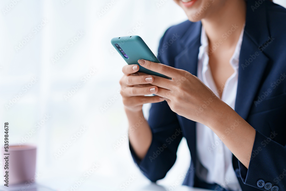 Close-up of a woman using a smartphone to work with customers via LINE messaging applications make financial transactions or play social media.