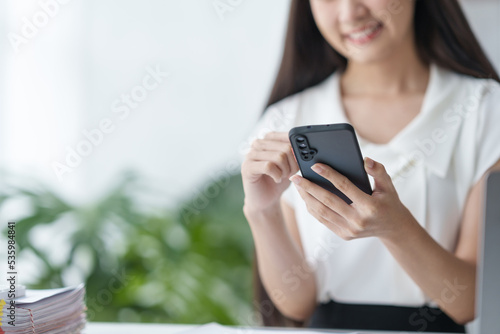 Close-up of a woman using a smartphone to work with customers via LINE messaging applications make financial transactions or play social media.