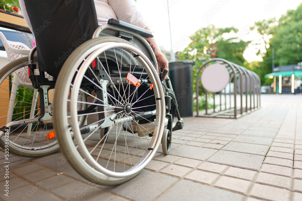 Unrecognizable woman with disability sitting in wheelchair in the street close up