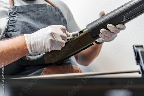 The gunsmith maintaining his rifle in a workshop