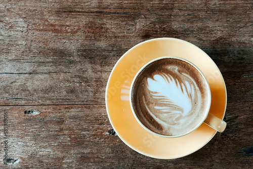 Top view of a latte art coffee on old wooden table.