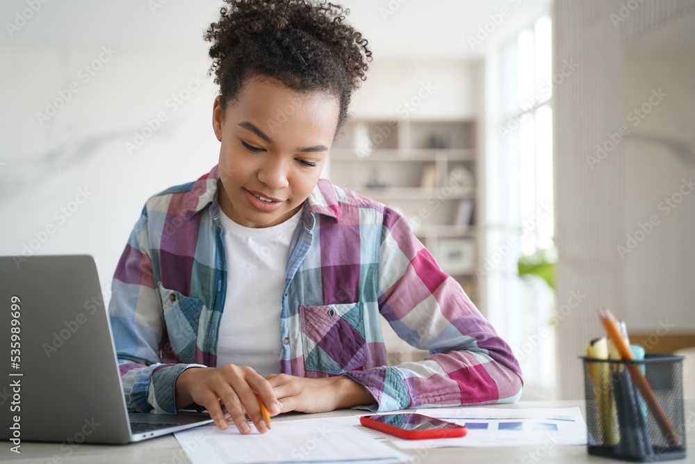 Mixed race girl school student studying at laptop, making homework at home. Distance education Mixed race girl school student studying at laptop, making homework at home. Distance education