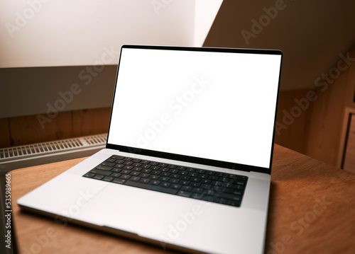 Aluminum professional laptop with empty screen open in modern interior. Concept of work from home. Blank screen notebook mock-up.