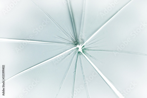 The hole in the broken and cracked glass on white background, closeup