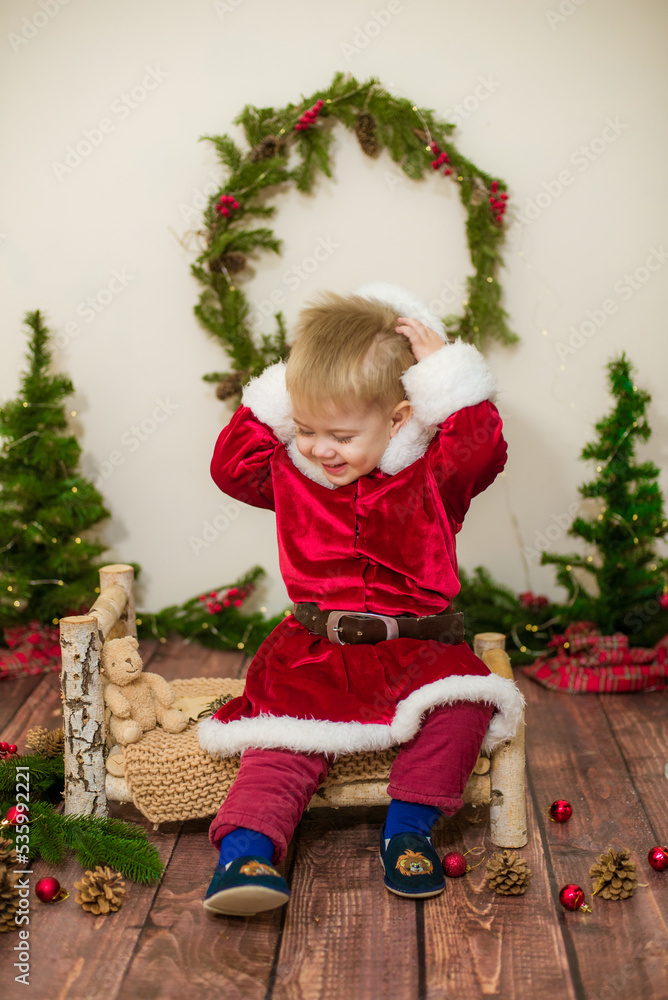Little cute boy dressed as Santa Claus in a room decorated for Christmas. Christmas and children Little cute boy dressed as Santa Claus in a room decorated for Christmas. Christmas and children