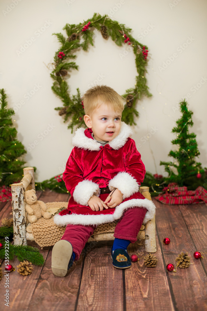 Little cute boy dressed as Santa Claus in a room decorated for Christmas. Christmas and children Little cute boy dressed as Santa Claus in a room decorated for Christmas. Christmas and children