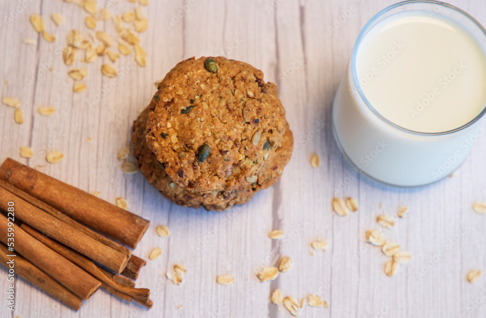 Oatmeal cookies, milk and cinnamon on  wooden background, top view