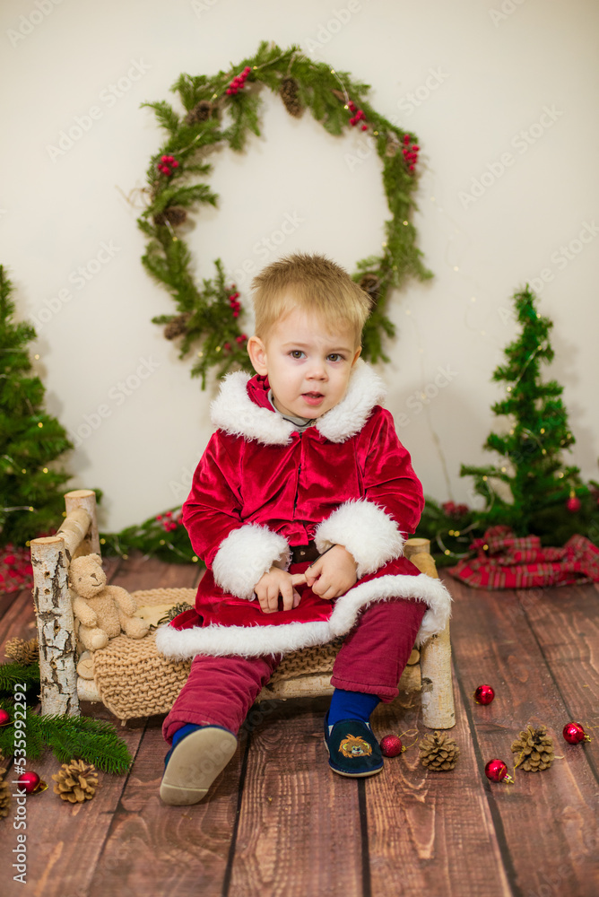 Little cute boy dressed as Santa Claus in a room decorated for Christmas. Christmas and children Little cute boy dressed as Santa Claus in a room decorated for Christmas. Christmas and children