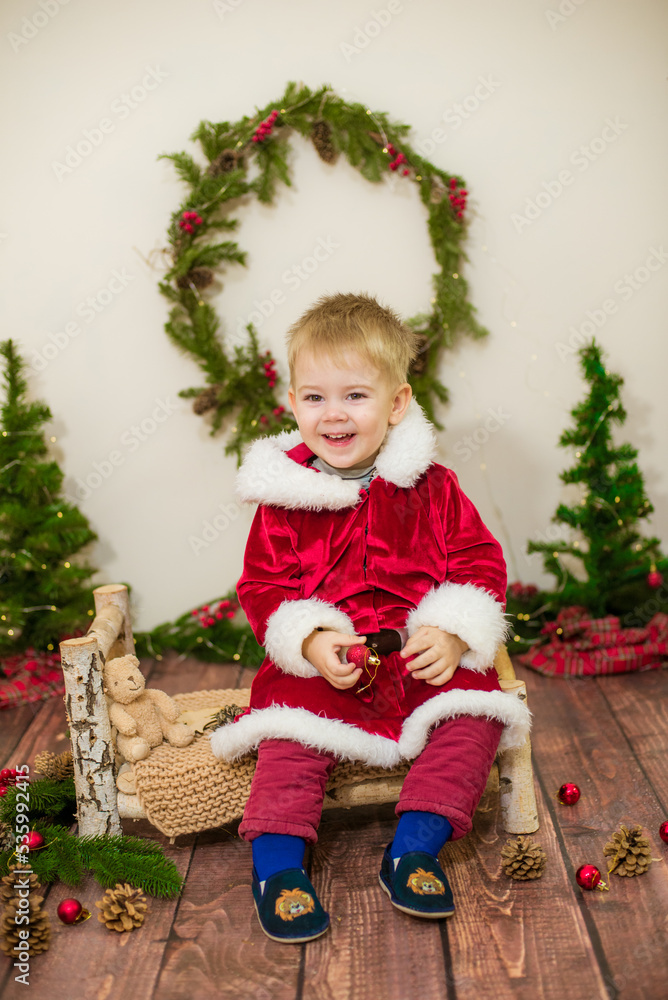 Little cute boy dressed as Santa Claus in a room decorated for Christmas. Christmas and children Little cute boy dressed as Santa Claus in a room decorated for Christmas. Christmas and children