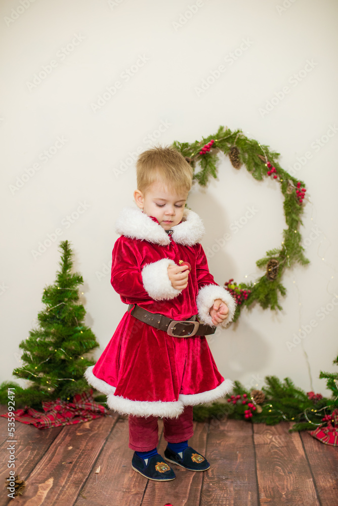 Little cute boy dressed as Santa Claus in a room decorated for Christmas. Christmas and children Little cute boy dressed as Santa Claus in a room decorated for Christmas. Christmas and children