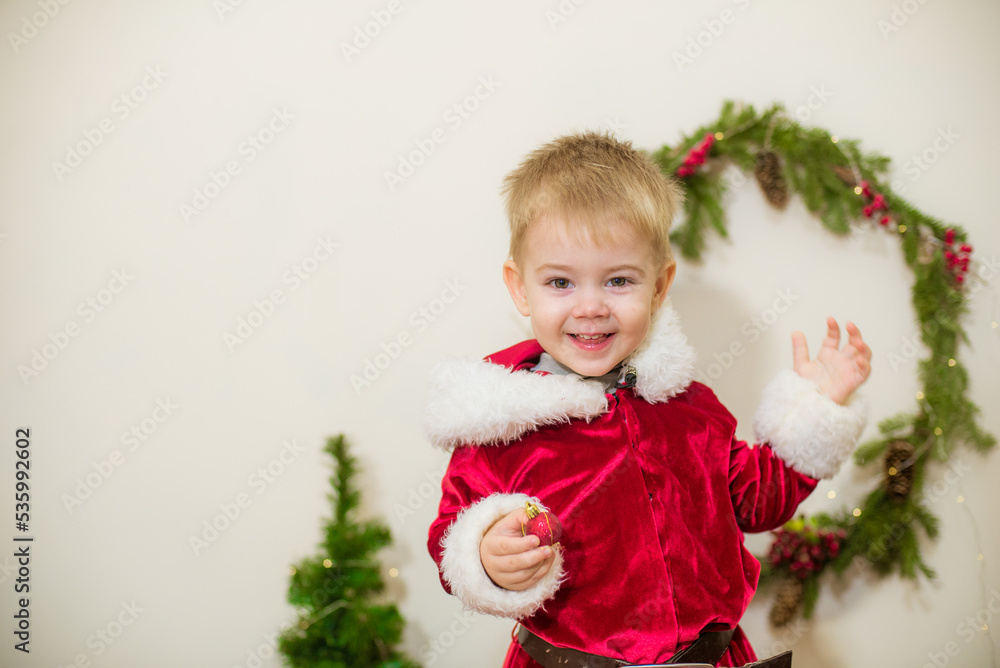 Little cute boy dressed as Santa Claus in a room decorated for Christmas. Christmas and children Little cute boy dressed as Santa Claus in a room decorated for Christmas. Christmas and children