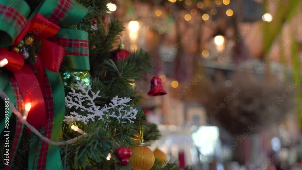 Close-up Christmas tree decorated with snowflake and red jingle bells with blurred sparkling fairy background..Festively Christmas and New Year party 2023 , Festival mood Winter holidays concept. Close-up Christmas tree decorated with snowflake and red jingle bells with blurred sparkling fairy background..Festively Christmas and New Year party 2023 , Festival mood Winter holidays concept.