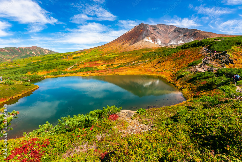 秋の北海道・大雪山の旭岳で見た、山頂近くの池周辺に広がる色鮮やかな紅葉と快晴の青空