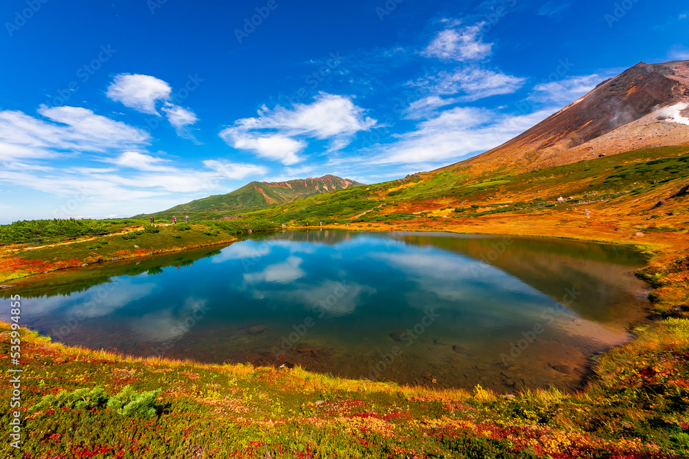 秋の北海道・大雪山の旭岳で見た、山頂近くの池周辺に広がる色鮮やかな紅葉と快晴の青空