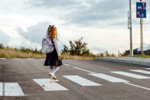 schoolgirl crosses the road at a pedestrian crossing