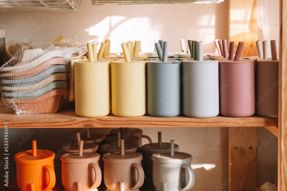 Multicolored silicone baby tableware stack with handles and forms on shelf of the store. Child healthcare, ecological utensil. Kid accessories equipment. Nutrition and feeding concept. Close up Multicolored silicone baby tableware stack with handles and forms on shelf of the store. Child healthcare, ecological utensil. Kid accessories equipment. Nutrition and feeding concept. Close up