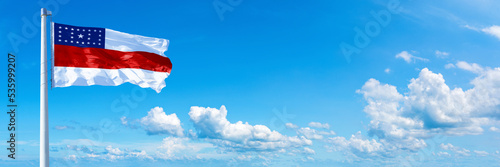 Amazonas - state of Brazil, flag waving on a blue sky in beautiful clouds - Horizontal banner
