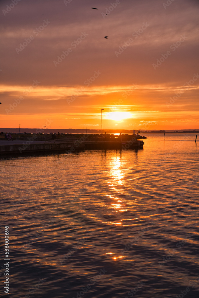 Sunset in Sweden at the harbor of lake Vaettern. Lighthouse in the background