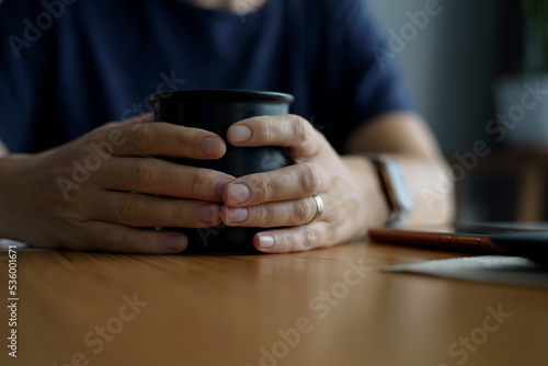   n female hands a black porridge with coffee sitting at the table
