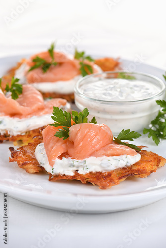 Crispy Potato fritters (a pancake, especially one made with grated potato) with cream cheese sauce with herbs and salmon