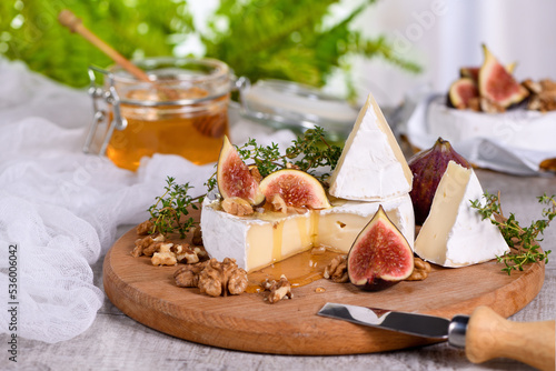 Quadro su tela Brie cheese served on a wooden board with figs, walnuts and honey