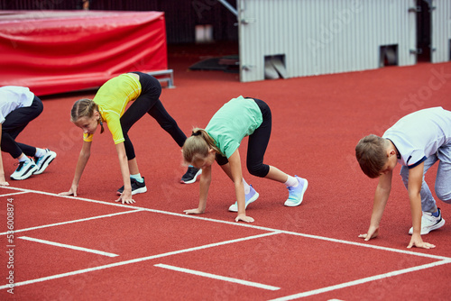 Start. Group of kids getting ready to run on treadmill at the stadium or arena. Little boys, girls in sportswear training as athletes outdoor. Concept of sport, achievements, studying, skills