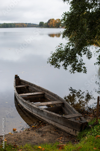 old wooden fishing boat stands on the lake in the village of autumn in cloudy weather.