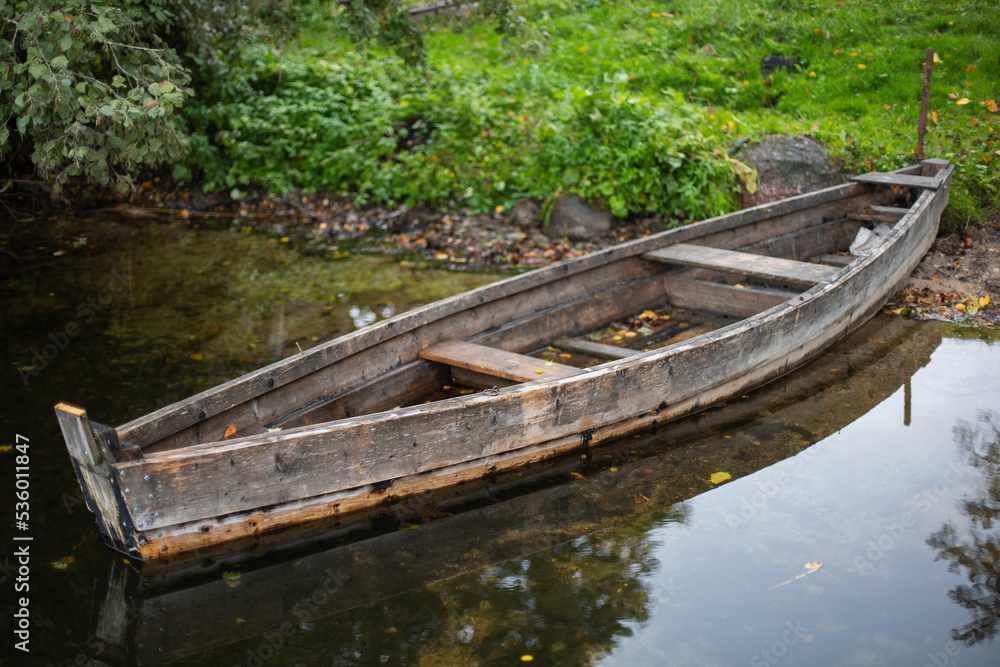 old wooden fishing boat stands on the lake in the village of autumn in cloudy weather.