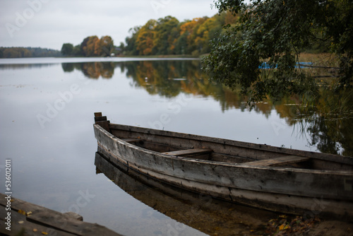 old wooden fishing boat stands on the lake in the village of autumn in cloudy weather.