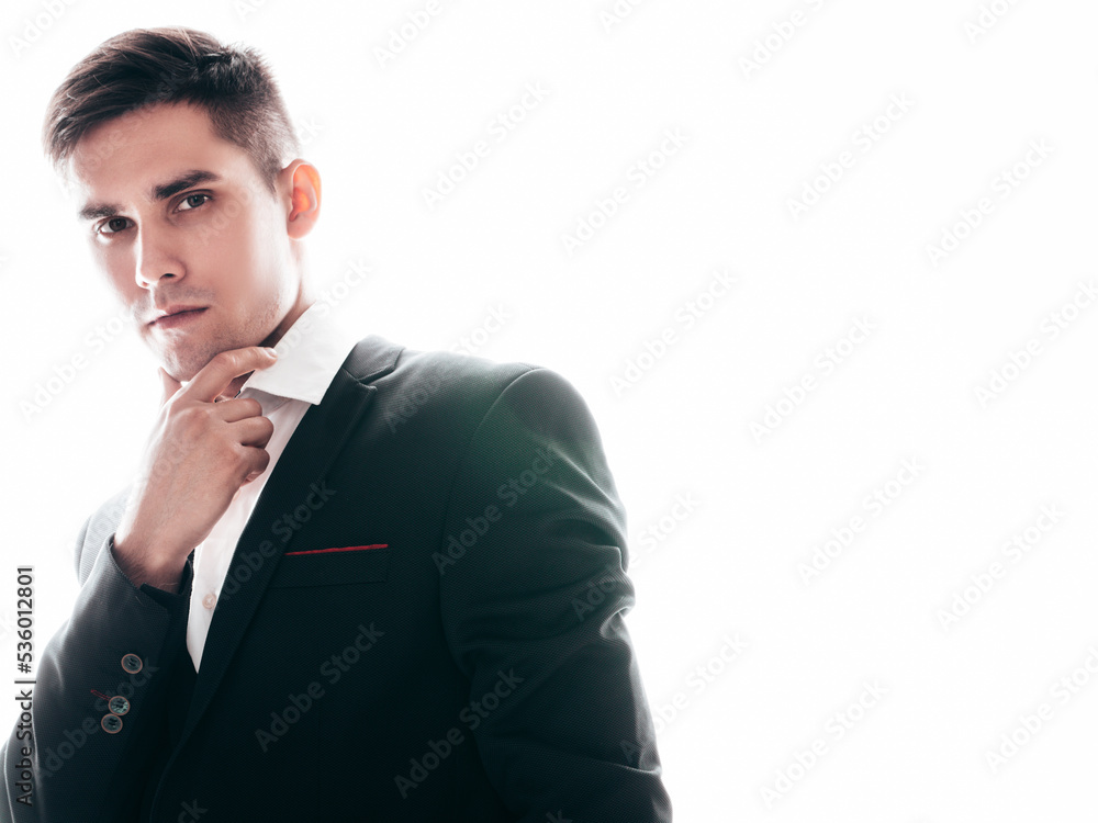 Portrait of handsome confident stylish hipster lambersexual model. Sexy modern man dressed in elegant black suit. Fashion male posing in studio near white wall. Isolated on white Portrait of handsome confident stylish hipster lambersexual model. Sexy modern man dressed in elegant black suit. Fashion male posing in studio near white wall. Isolated on white