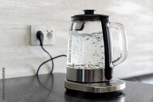 Transparent electric kettle with boiling water in the kitchen photo