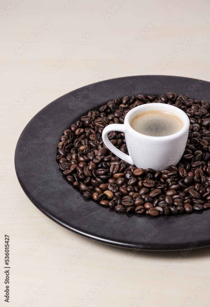 Roasted coffee espresso beans on dark plate background and cup with crema, close-up still life hot beverage, I love coffee concept Roasted coffee espresso beans on dark plate background and cup with crema, close-up still life hot beverage, I love coffee concept