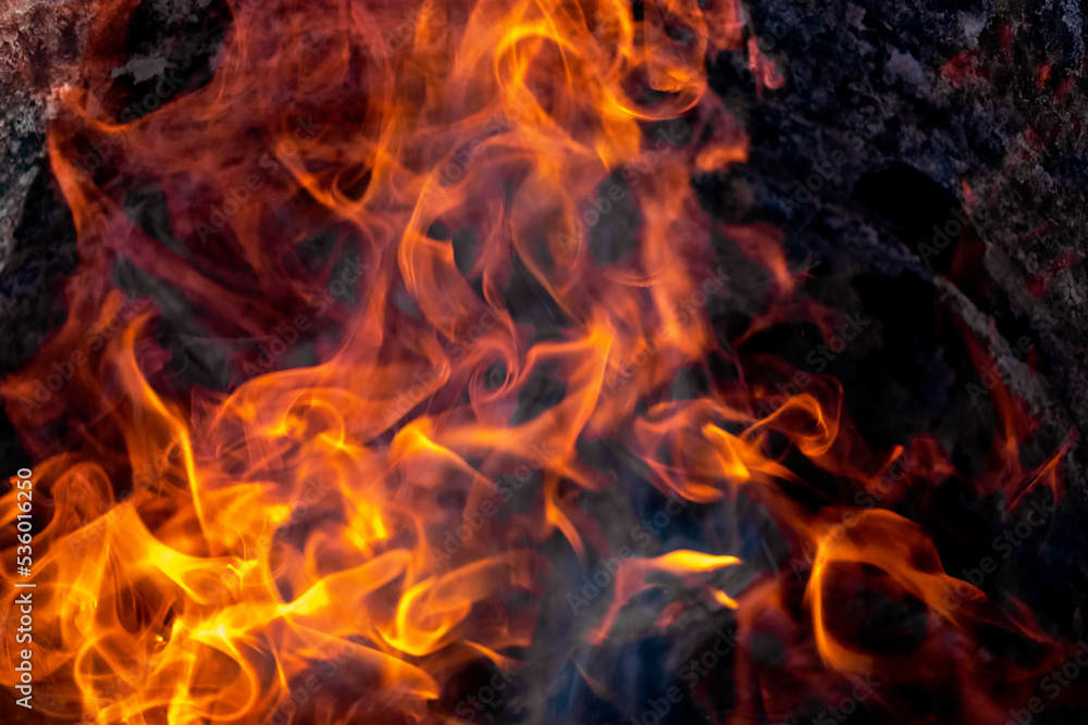 Burning fire close up. Bright orange and red flames on a dark background. Open flame heating. Problems with heating and gas. Burning fire close up. Bright orange and red flames on a dark background. Open flame heating. Problems with heating and gas.
