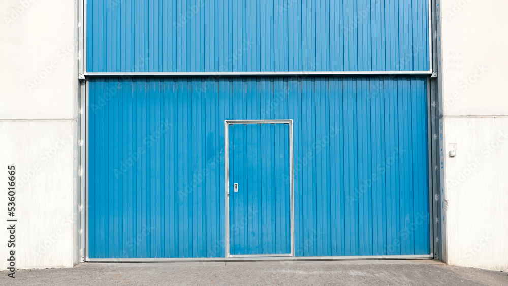 Puerta metálica azul en nave industrial de hormigón Puerta metálica azul en nave industrial de hormigón