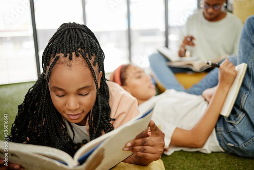 Education, study and learning students group of people studying for test, exam or doing research project on school campus. University, young college friends or a relax gen z black woman reading books photo