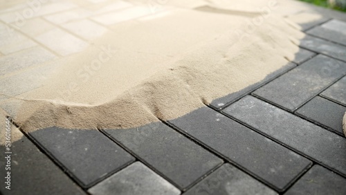 Laying tiles in the garden of the city park. Sand for paving slabs. Work on laying paving slabs in the park.