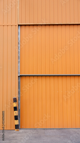 Puerta metálica naranja en nave industrial de hormigón 