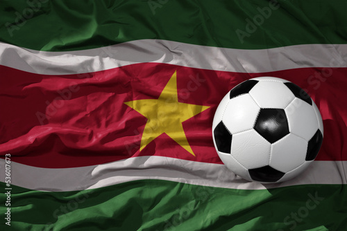 vintage football ball on the waveing national flag of suriname background. 3D illustration